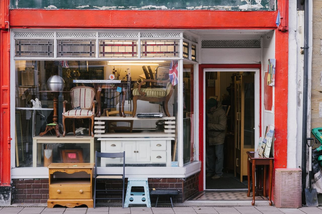 A charming storefront with vintage furniture and shop window on a city sidewalk.